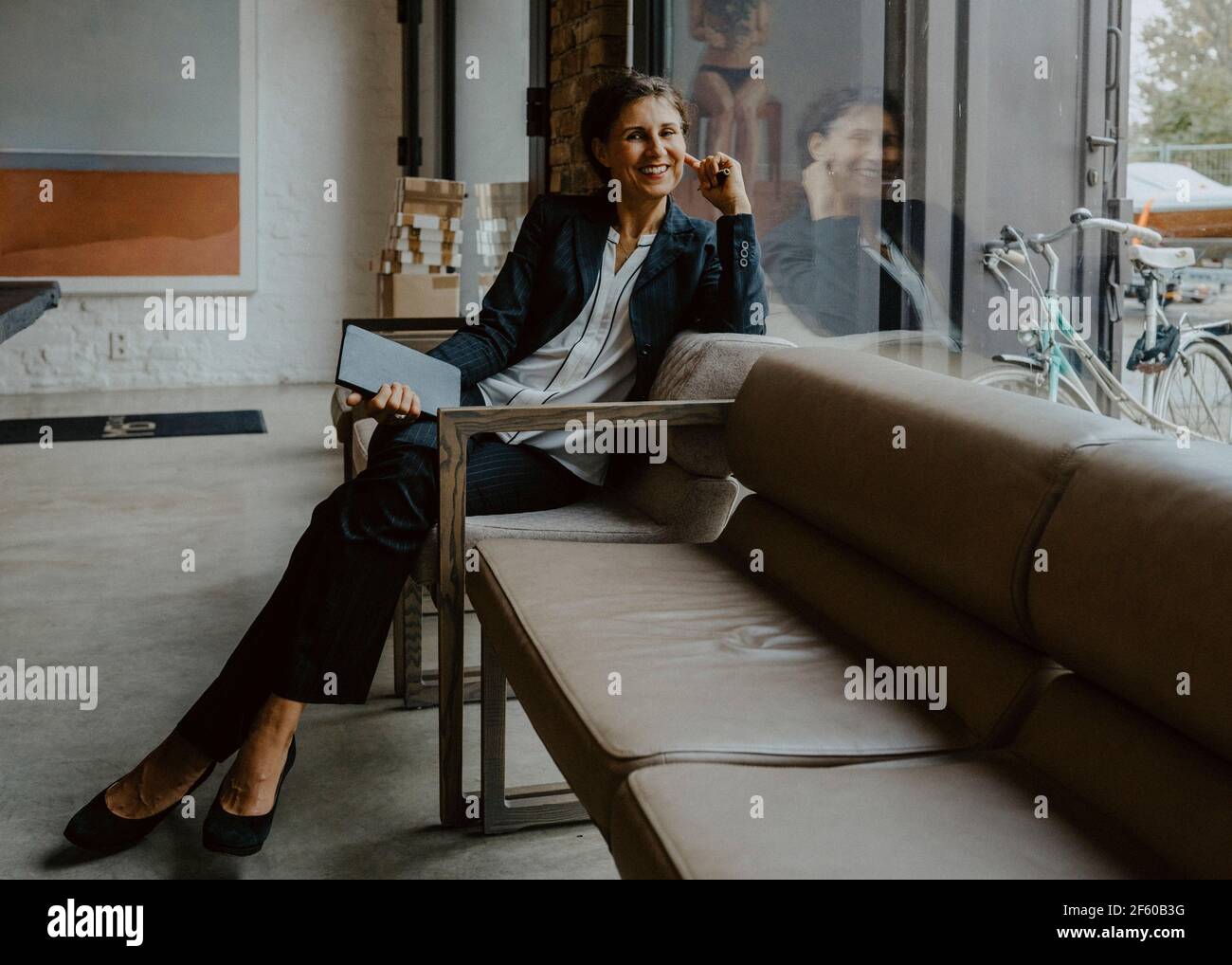 Ritratto di sorridere imprenditrice seduta sul divano in ufficio Foto Stock
