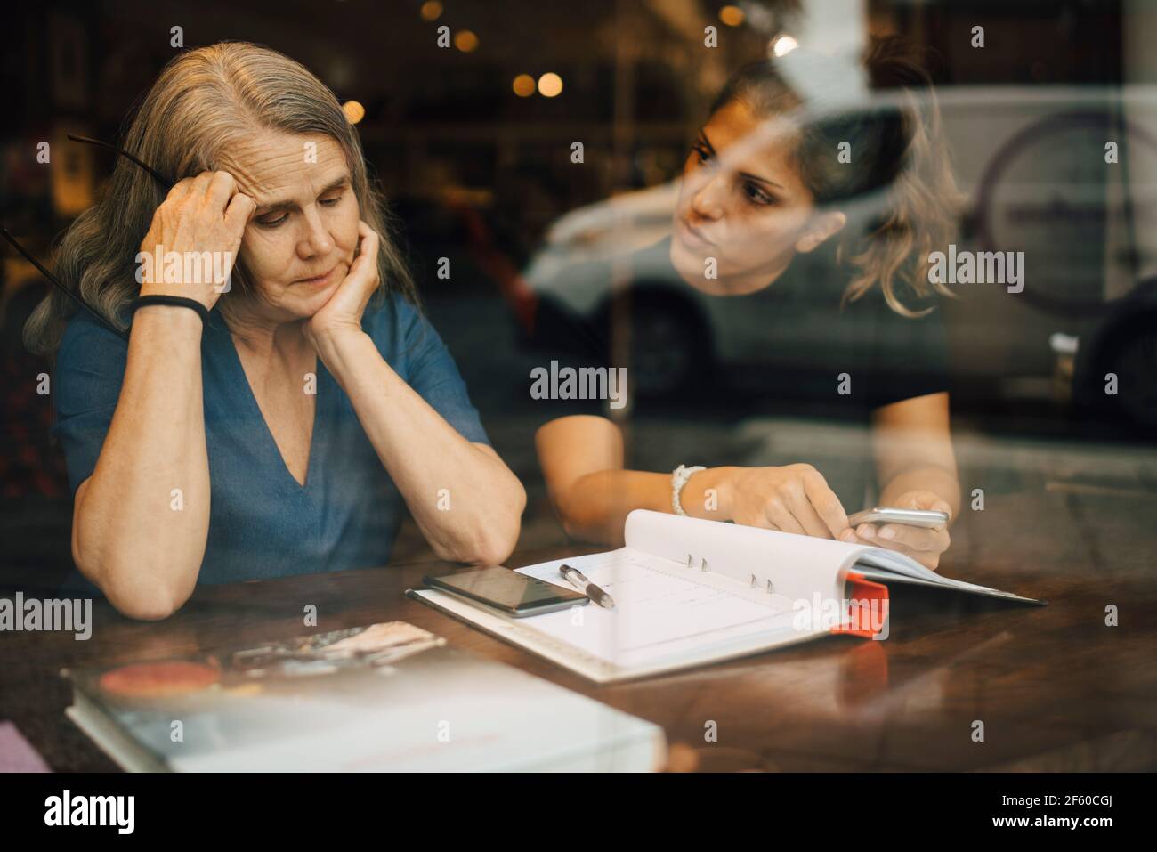 Le donne che discutono hanno visto attraverso il vetro del negozio al dettaglio Foto Stock