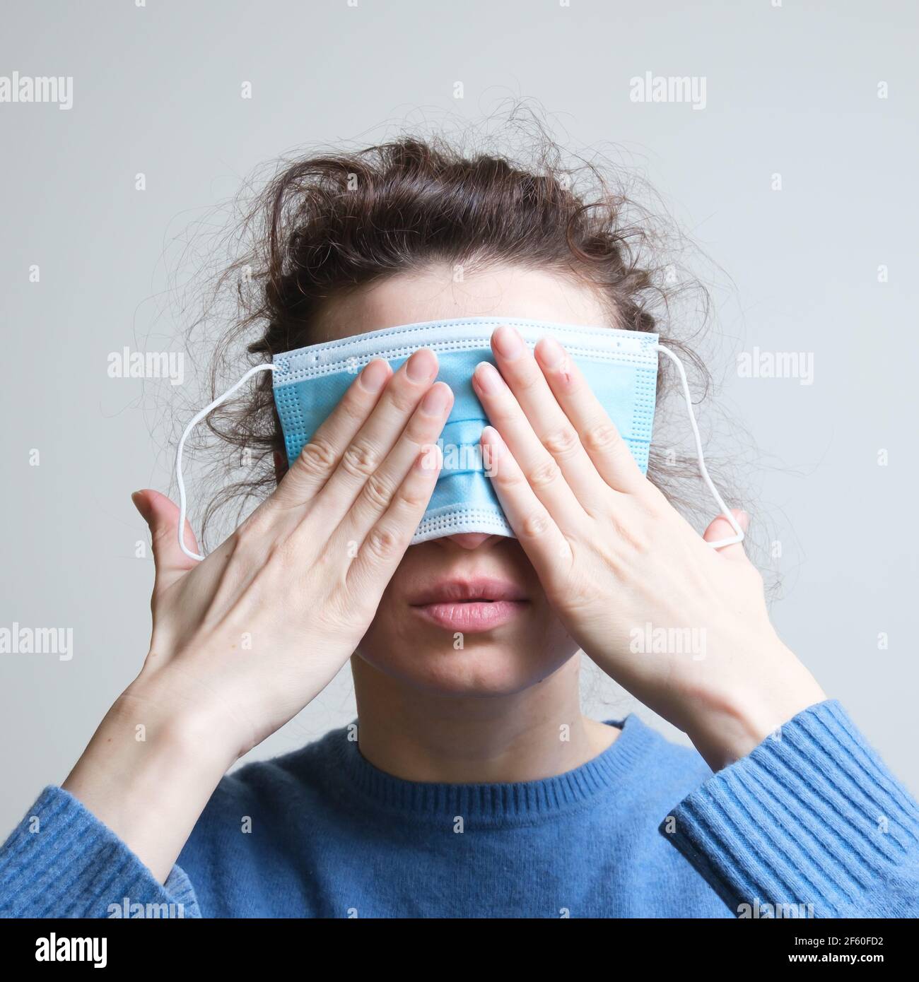 La ragazza copre gli occhi, la bocca e le orecchie con una maschera Foto Stock