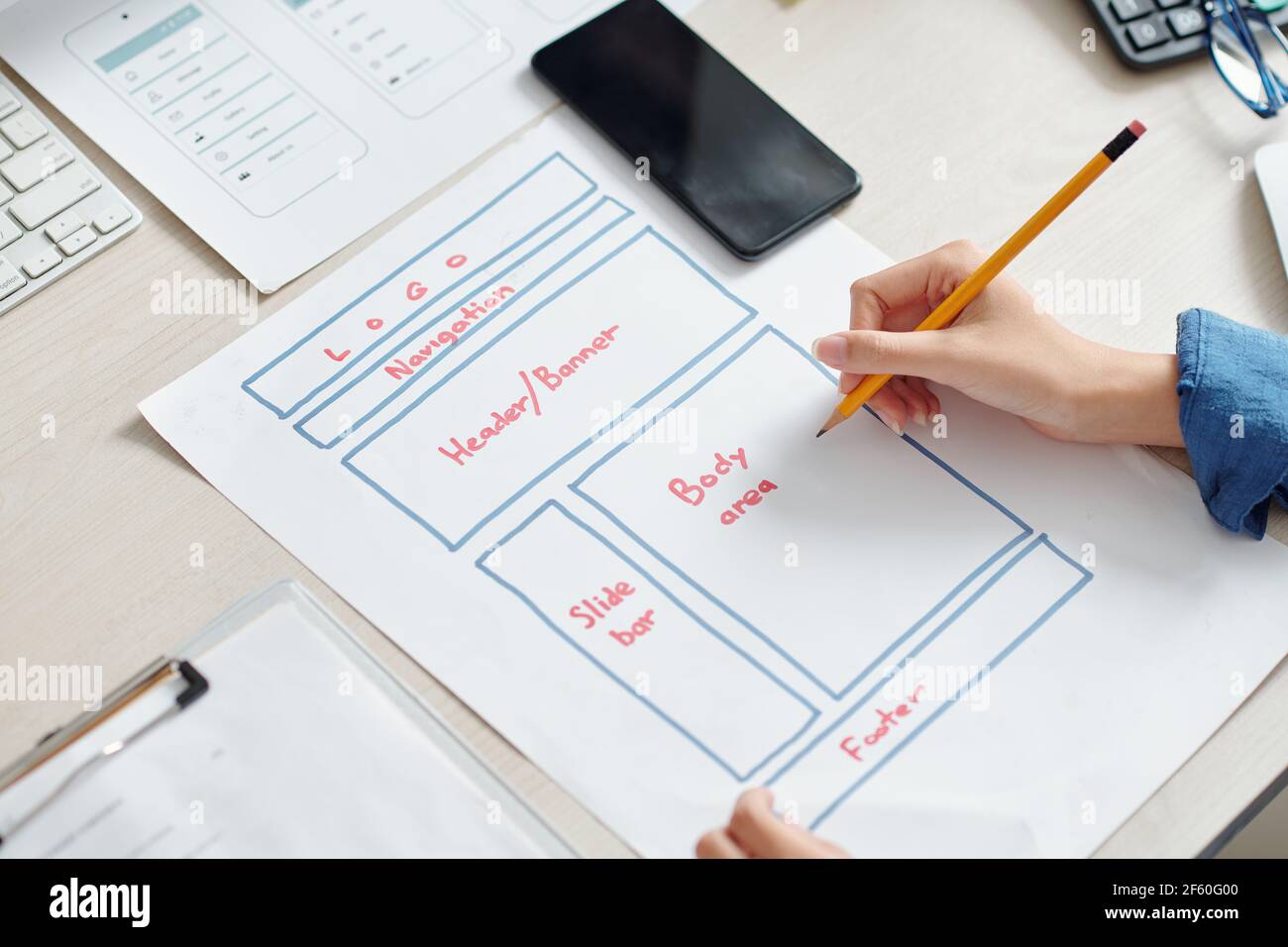 Mani di designer UI creativo disegno di layout di interfaccia per applicazioni mobili su foglio di carta Foto Stock