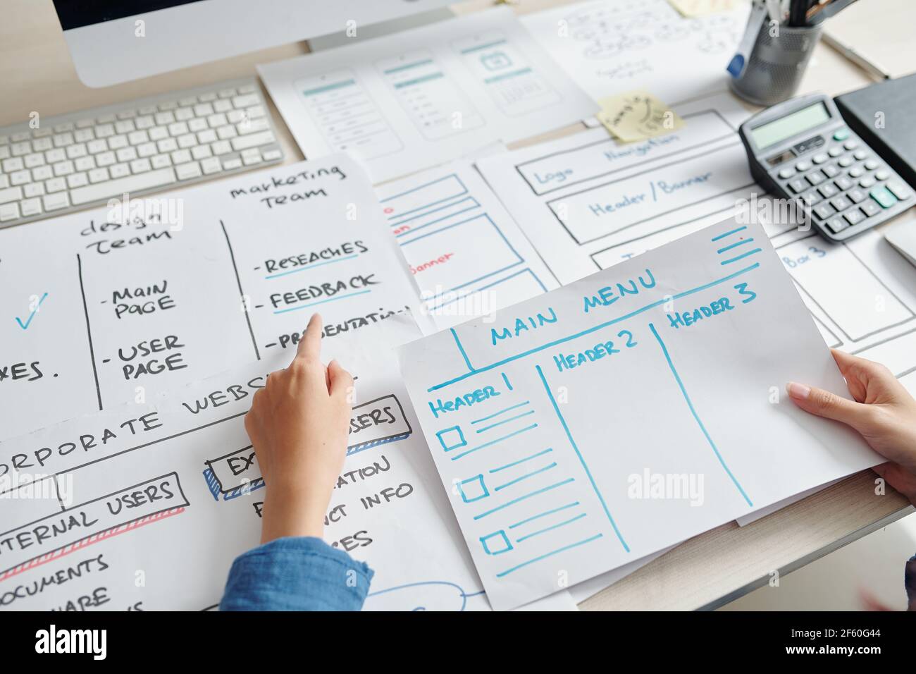 Il progettista UX analizza i layout di fronte a lui durante la creazione layout dell'interfaccia del sito web della nuova azienda Foto Stock