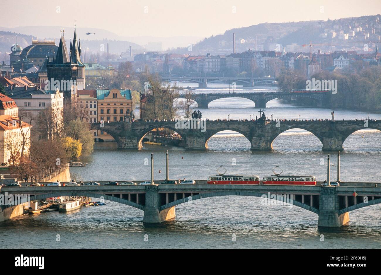 2002 Praga - tre ponti sul fiume Moldava skyline di Praga Repubblica Ceca Europa. L'elicottero si aggira sopra la città vecchia.i tram attraversano il primo ponte, il ponte Manes (Mánesův la maggior parte) e la folla attraversa il ponte Carlo (Karlův Most), il secondo ponte. Foto Stock
