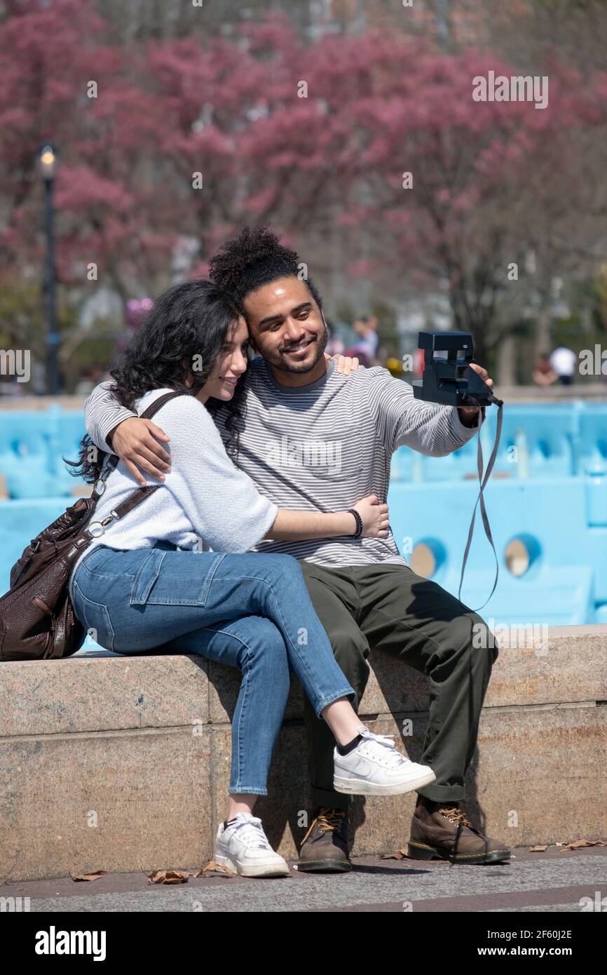 Una vecchia coppia di scuola prende un selfie con una macchina fotografica Polaroid. Nel Flushing Meadows Corona Park a Queens, New York City Foto Stock