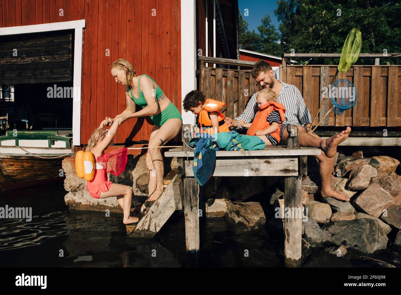 Padre con bambini seduti sul molo durante le vacanze estive Foto Stock