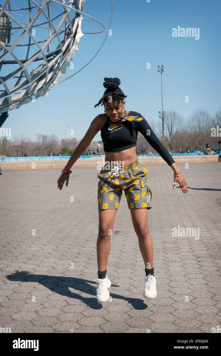 Una bella donna del Ghana registra le routine di danza vicino all'Unisphere nel Flushing Meadows Corona Park a Queens, New York City. Foto Stock