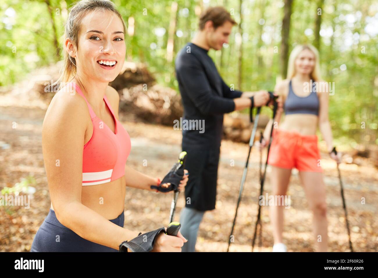 Giovane donna sportiva con amici mentre nordic walking in natura in estate Foto Stock