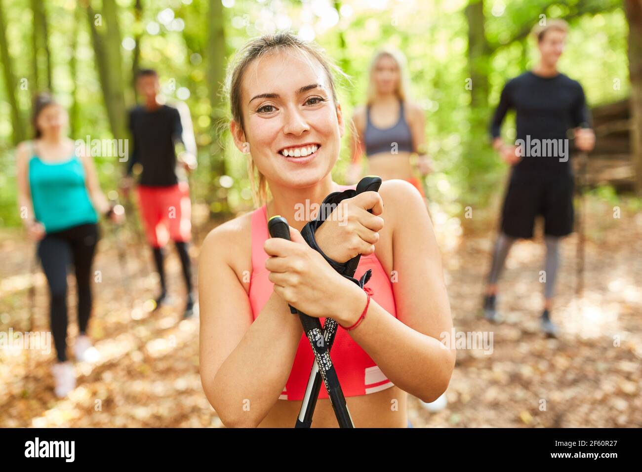 Felice giovane donna come allenatore di fitness con i suoi nordici gruppo escursionistico a piedi Foto Stock