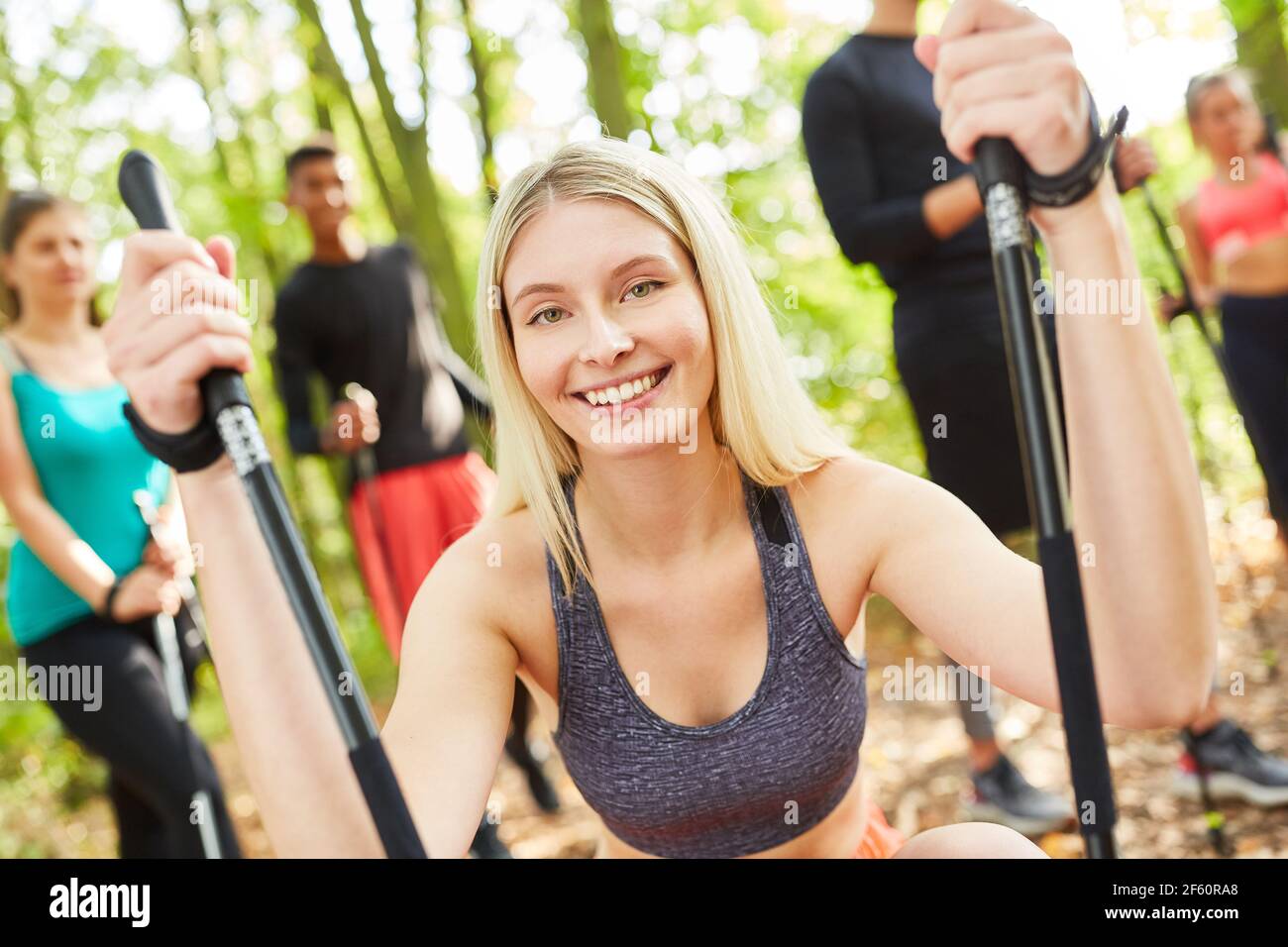 Giovane donna come allenatore di fitness con gruppo mentre nordico passeggiate nella natura in estate Foto Stock