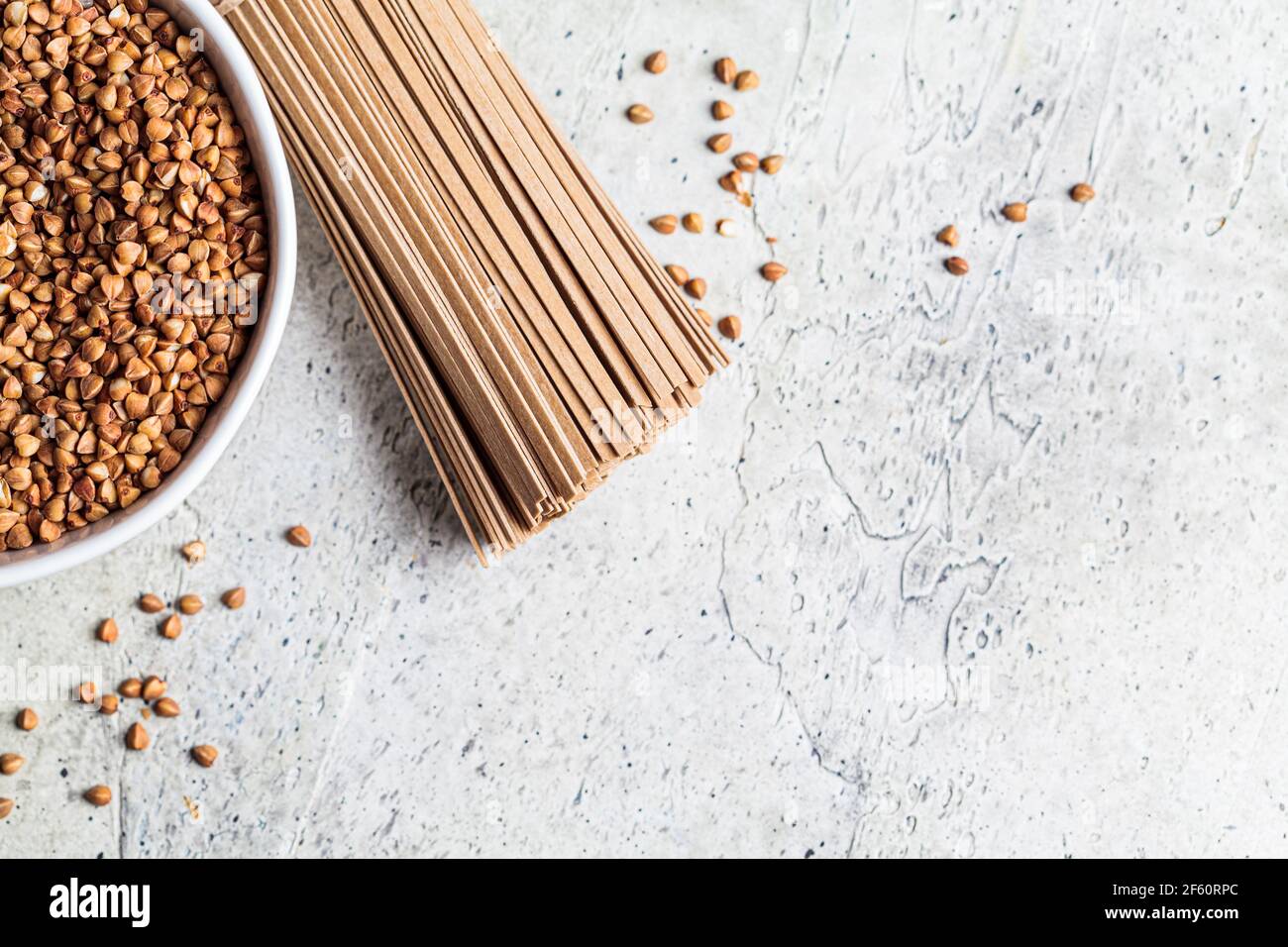 Soba cruda - tagliatelle di grano saraceno e grano saraceno in una ciotola bianca. Concetto di cibo sano. Foto Stock