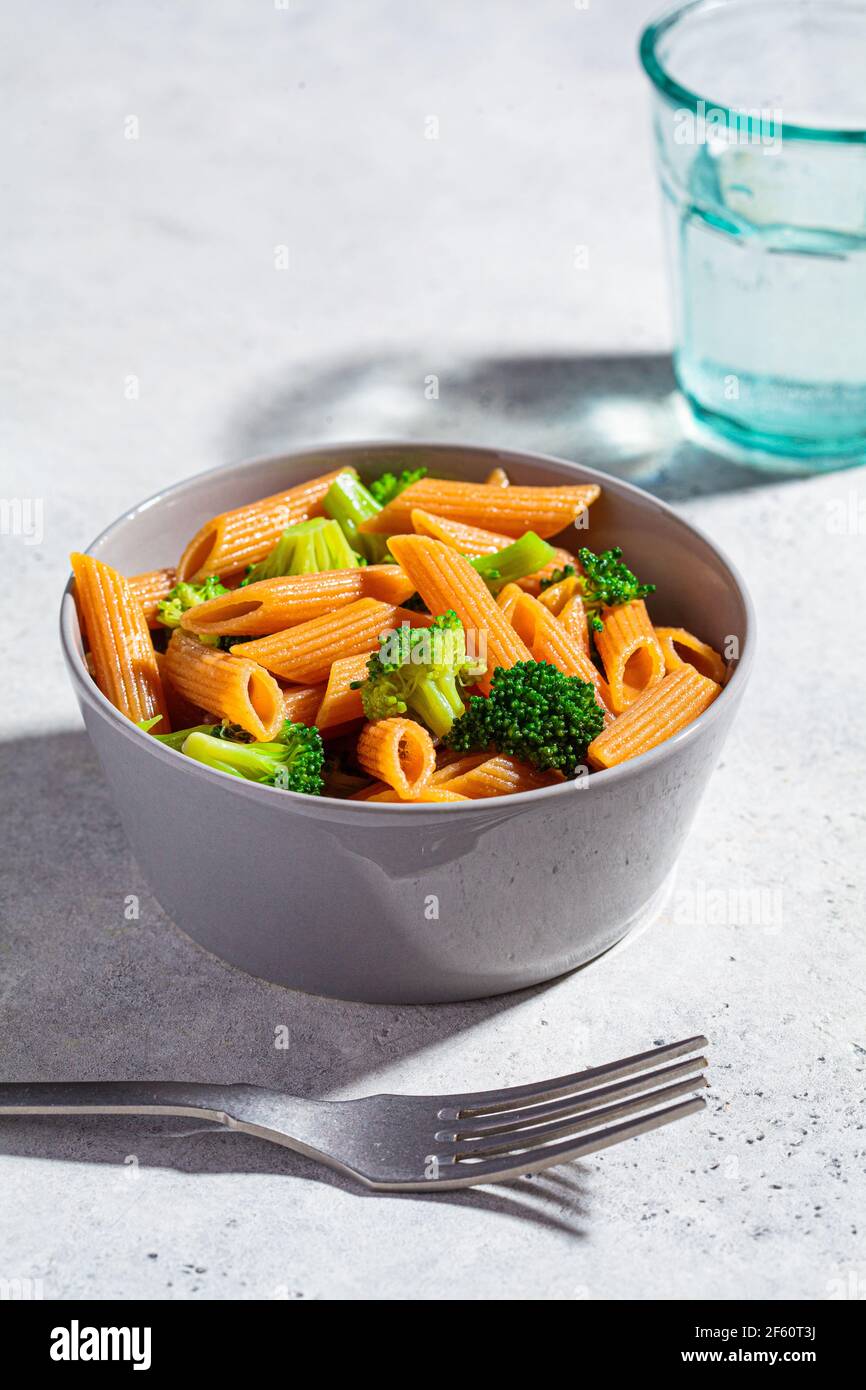 Pasta di lenticchie rosse con broccoli in una ciotola grigia. Sana pasta vegana con verdure. Foto Stock