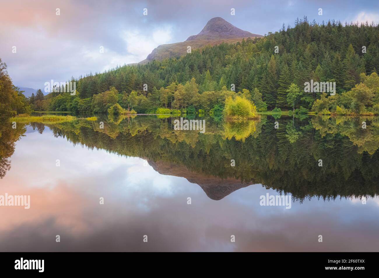 Calmo, idilliaco paesaggio montano lago riflesso del Pap of Glencoe su Glencoe Lochan durante il tramonto o l'alba nelle Highlands scozzesi, Scozia. Foto Stock