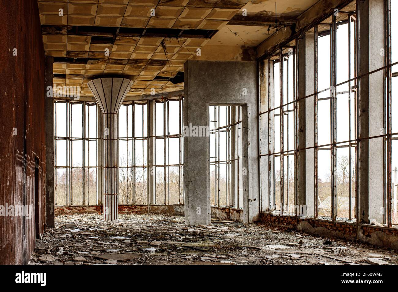 La sala in rovina di un vecchio edificio con ampie finestre. Vetro rotto sul pavimento. Foto Stock