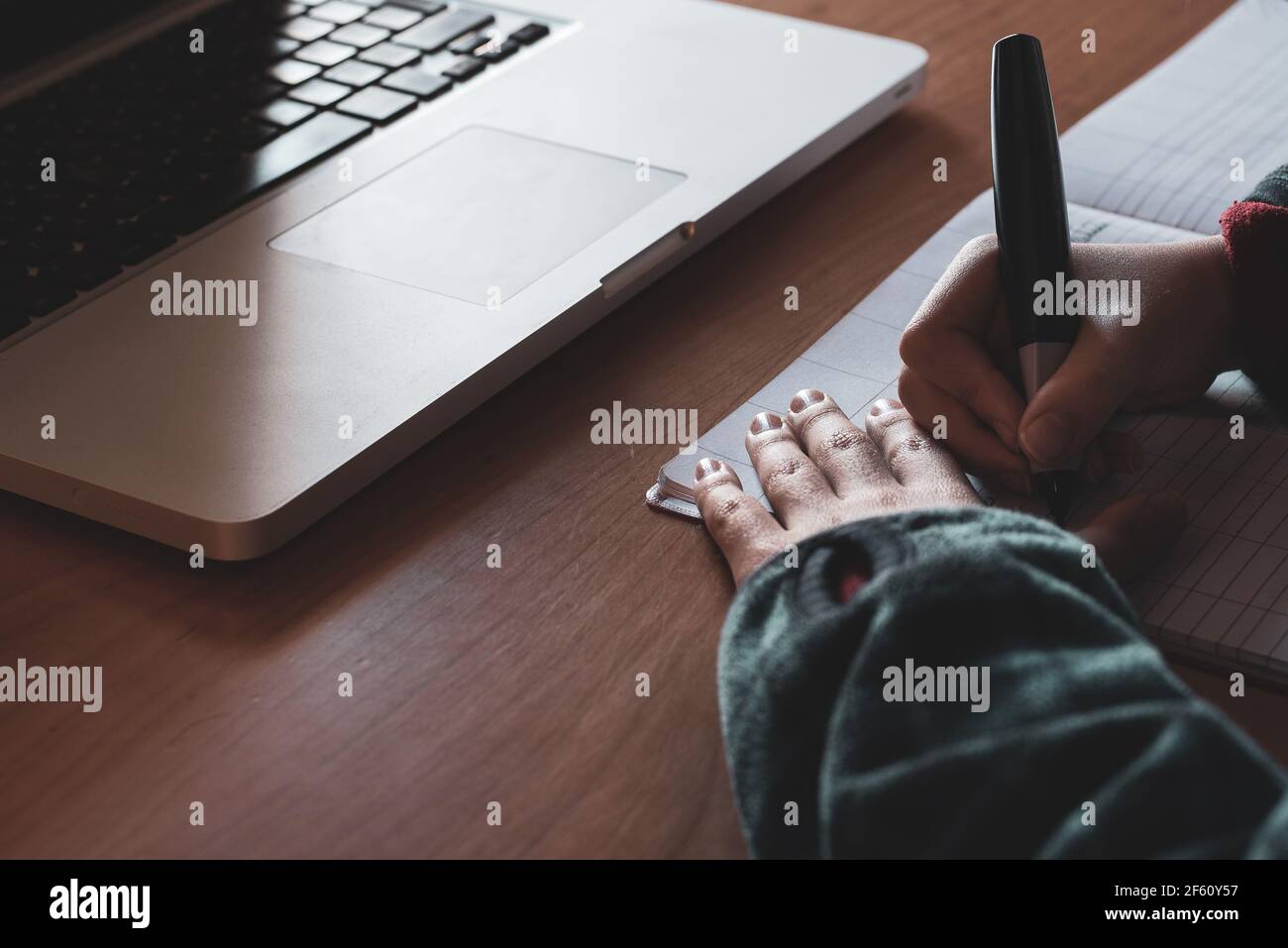 Mani di un ragazzo che scrivono su un notebook e un computer portatile. Concetto di esercitazione. Foto Stock