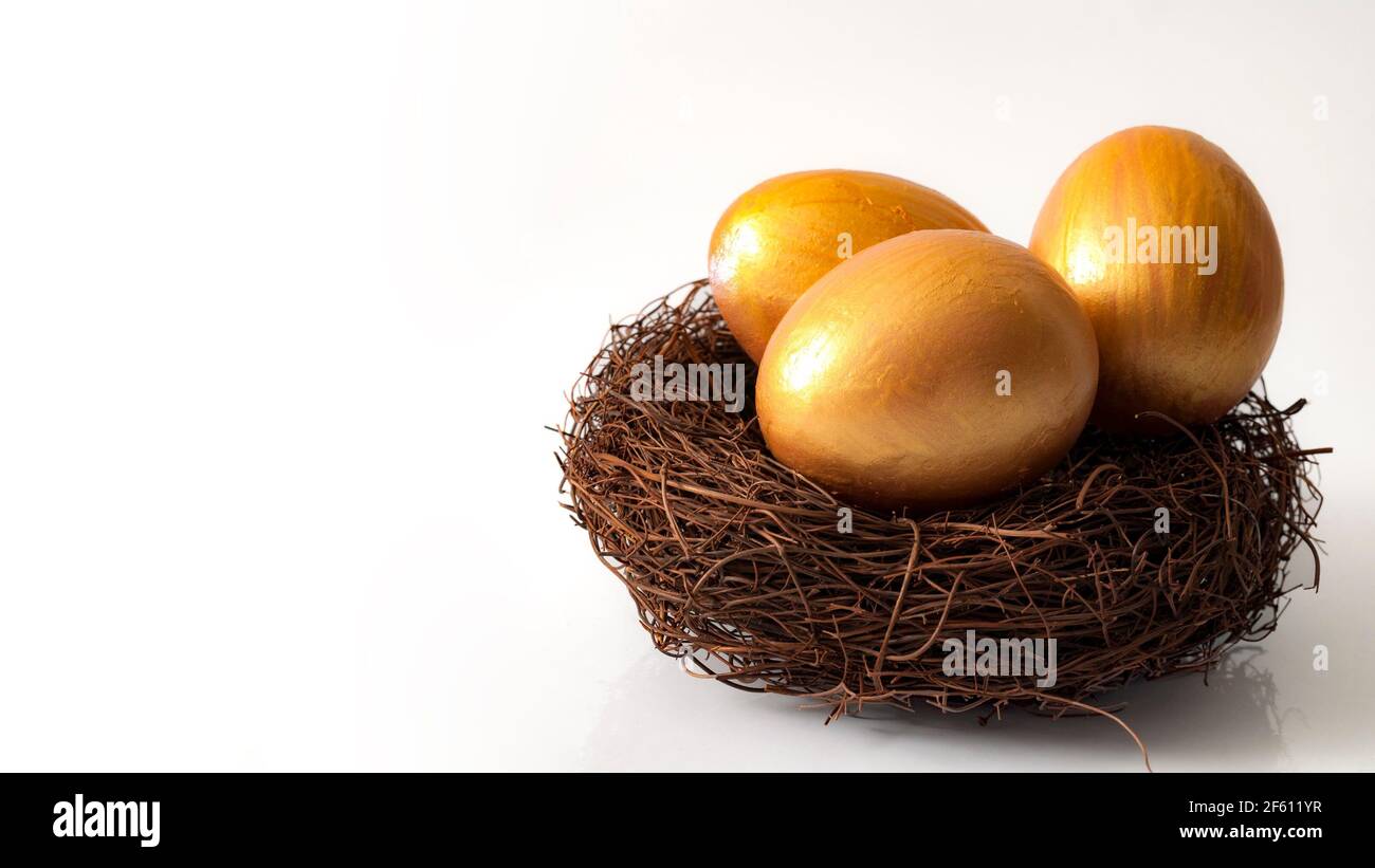 Investimento finanziario e concetto di pensionamento con tre uova d'oro in un nido isolato su bianco con spazio di copia Foto Stock
