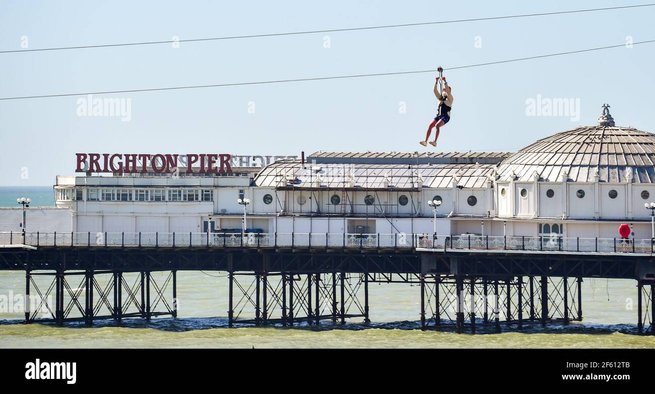 Brighton UK 29 marzo 2021 - il giro in Zipwire di Brighton è aperto poiché i visitatori godono di una bella giornata di sole, in quanto le restrizioni di blocco hanno iniziato a diminuire in Inghilterra le temperature dovrebbero raggiungere la metà degli anni 20 in alcune parti del Sud-est nei prossimi giorni. : Credit Simon Dack / Alamy Live News Foto Stock