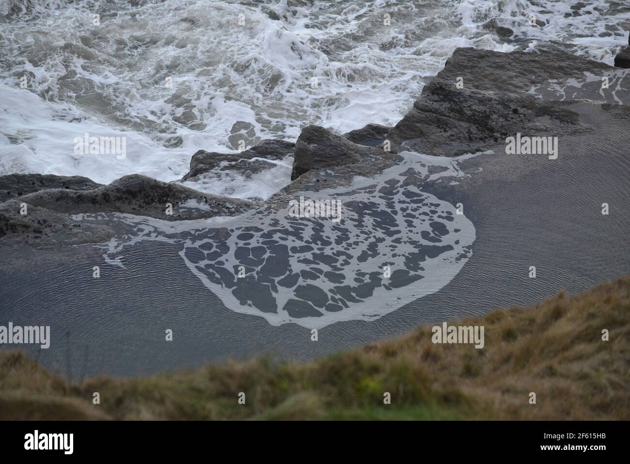 Piscina di mare naturale - Mare del Nord a Filey Brigg - schiuma di mare bianco - mare agugnoso Foto Stock