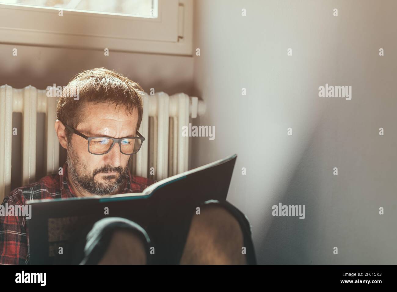 Casual mid adult maschio con occhiali ama leggere un libro a casa, headshot ritratto con fuoco selettivo Foto Stock