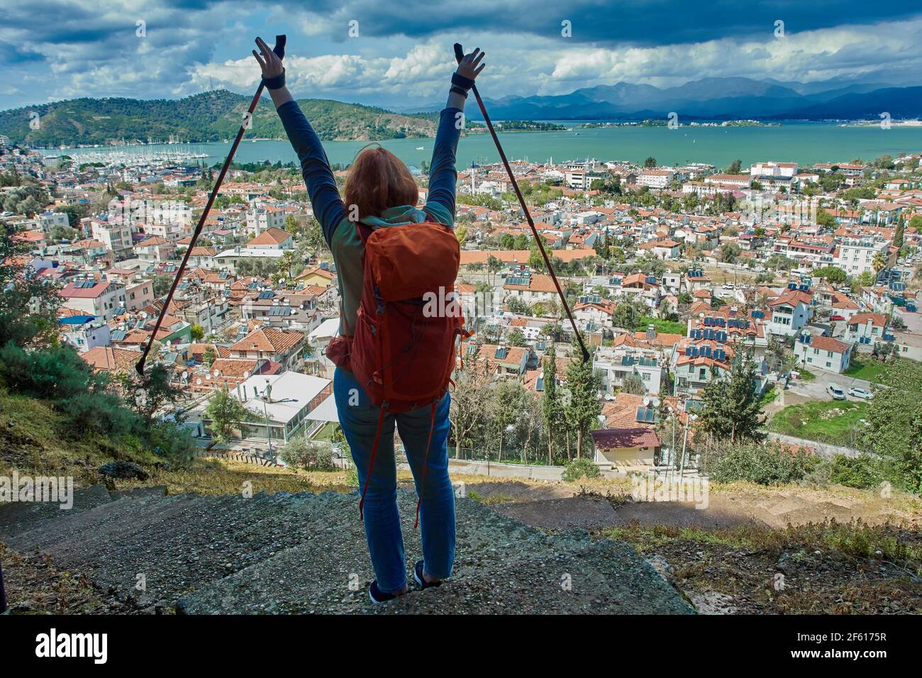 Escursionista o zaino in spalla ha alzato le mani con bastoni da passeggio,  in piedi sopra il panorama della città di Fethiye e resort in Turchia in  primavera Foto stock - Alamy