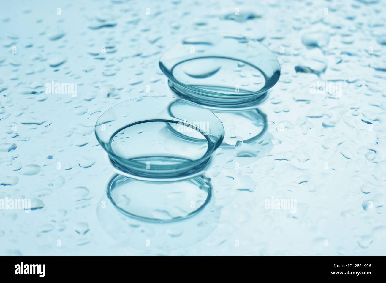Lenti a contatto con gocce su sfondo blu-verde lucido. Foto Stock