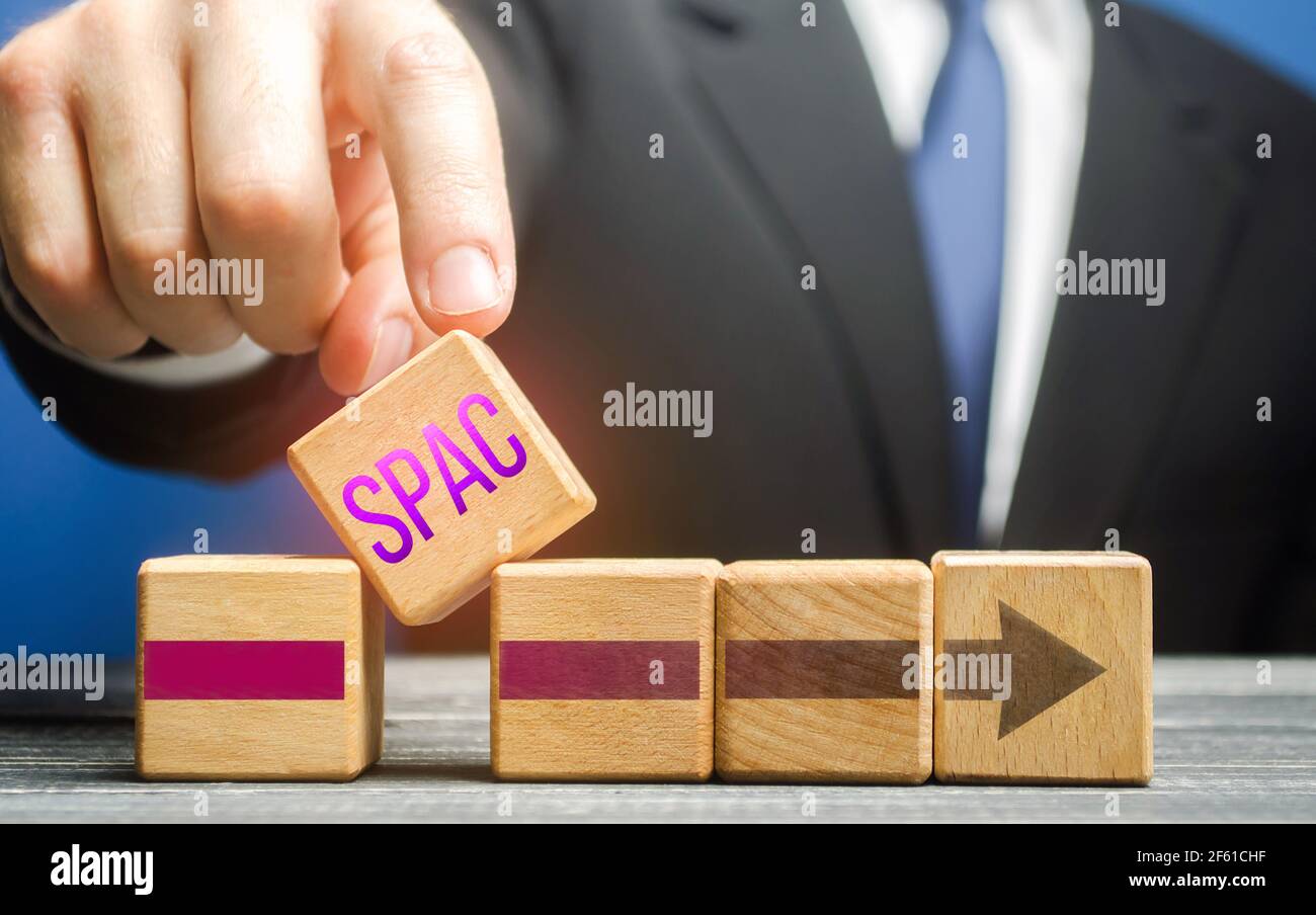 Man introduce un blocco con una parola SPAC in una riga. Uno strumento finanziario di borsa facile senso per attrarre gli investimenti, vendere le obbligazioni di riserva invece Foto Stock