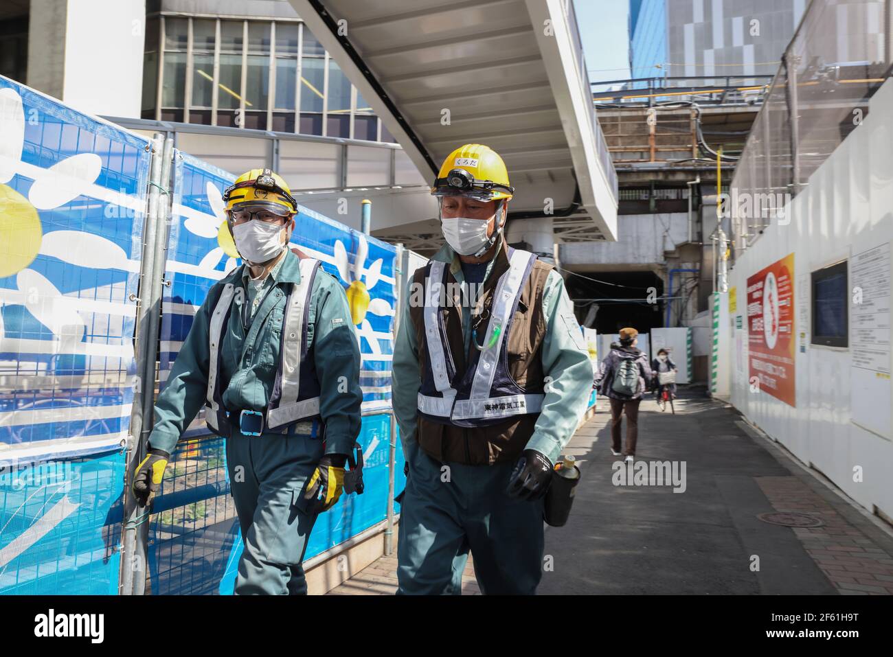 Tokyo, Giappone. 24 Marzo 2021. I lavoratori edili che indossano maschere facciali come misura preventiva contro Covid-19 camminano su una strada vicino Shibuya Station.amid Covid-19 pandemic l'economia del Giappone sta facendo meglio che nel resto del mondo. Meno restrizioni di blocco e un piccolo numero di infezioni hanno contribuito alla stabilità continua dell'economia giapponese. (Foto di Stanislav Kogiku/SOPA Images/Sipa USA) Credit: Sipa USA/Alamy Live News Foto Stock