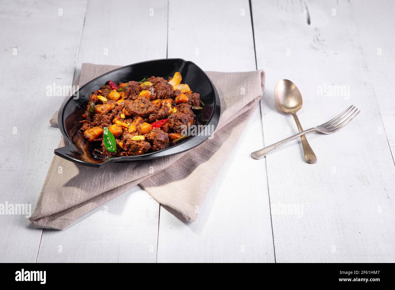 Arrosto di manzo o pothu ulartheyadu, piatto speciale kerala disposto in una tavola e guarnito con pezzi di cocco su uno sfondo di colore bianco. Foto Stock