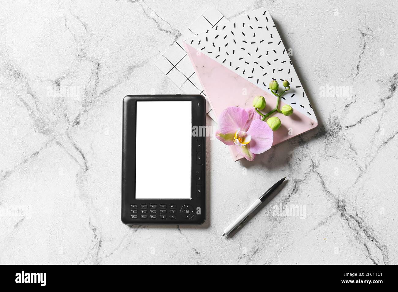 E-reader, taccuini e orchidea fiore su sfondo chiaro Foto Stock
