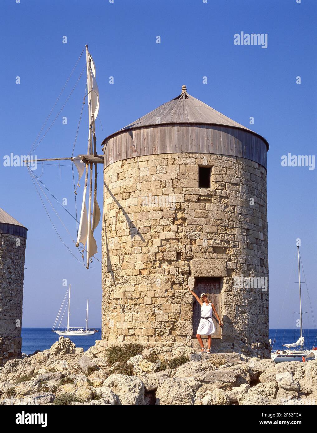 Giovane donna di vecchio mulino a vento in pietra, porto di Mandraki, Città di Rodi, Rodi, Dodecanese, Grecia Foto Stock