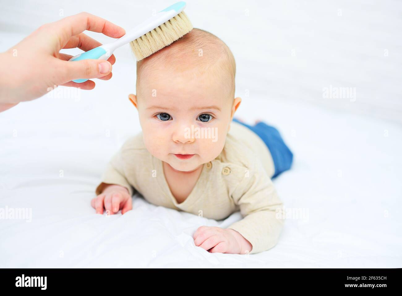 la mamma pettina il bambino con una speciale spazzola per capelli su sfondo bianco. Foto Stock
