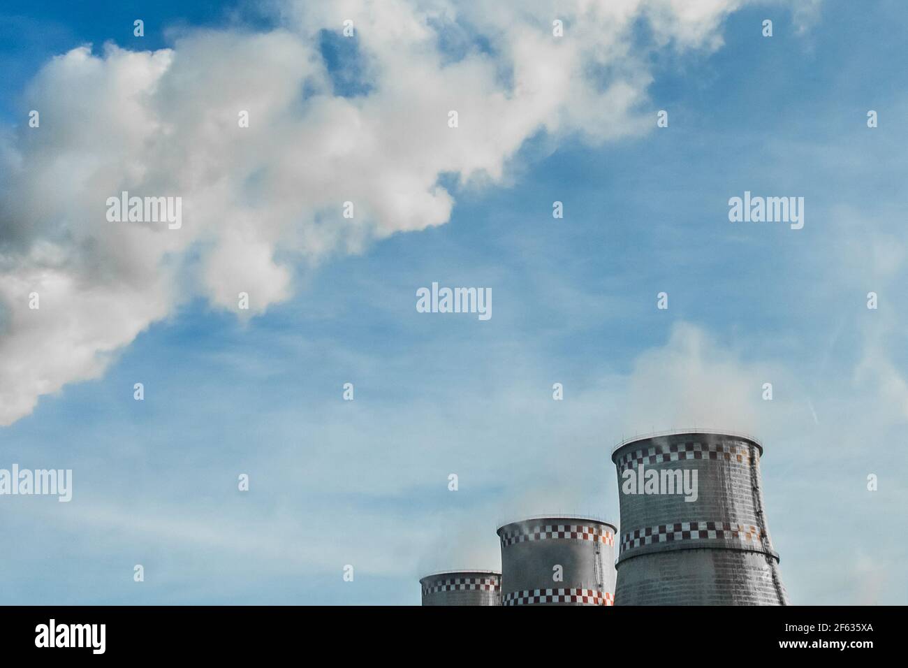 Torre di raffreddamento e fumo di un impianto industriale o di una centrale termica contro un cielo blu. Foto Stock