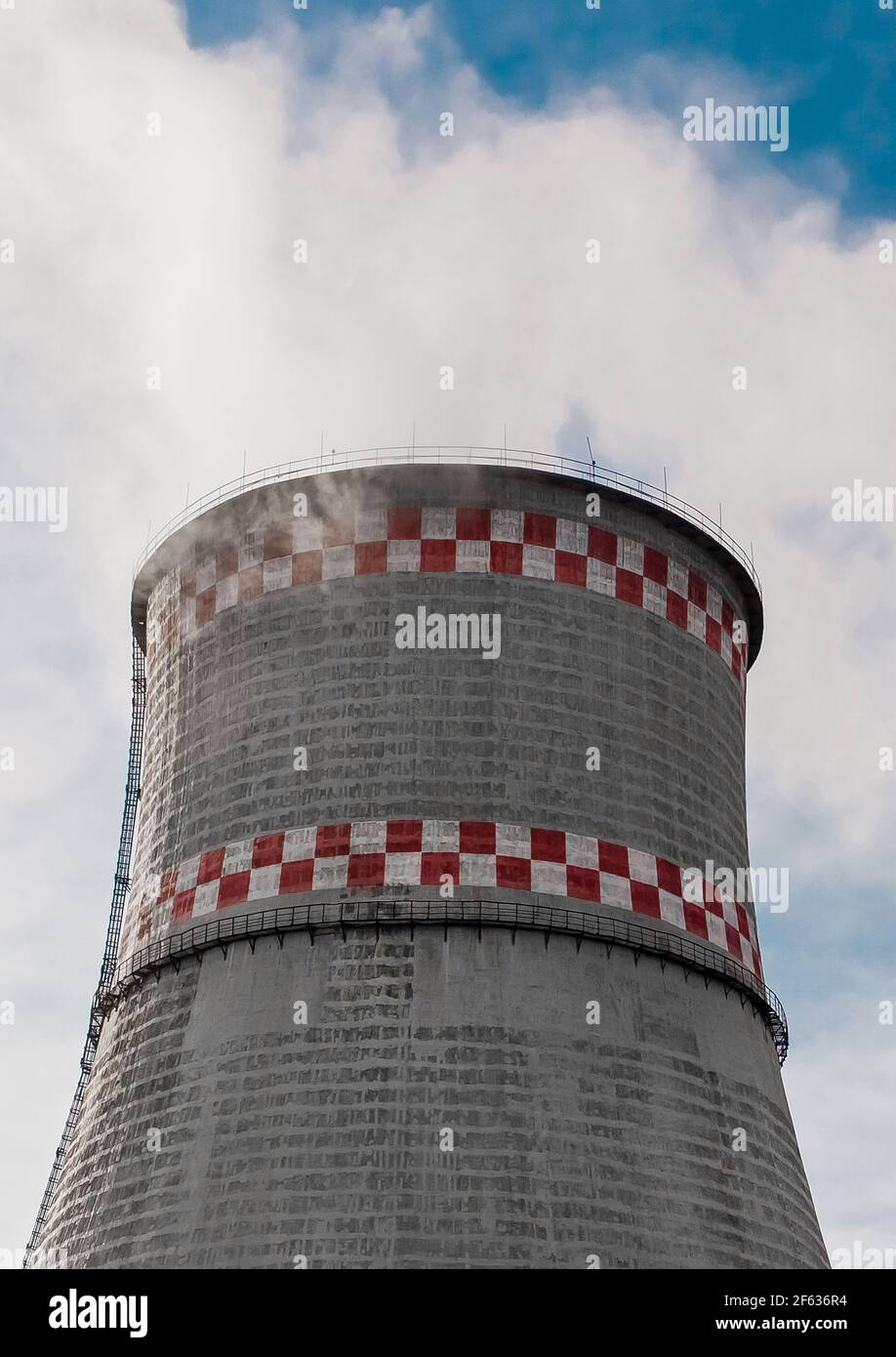 Torre di raffreddamento di un impianto industriale o di una centrale termica contro un cielo blu. Foto Stock