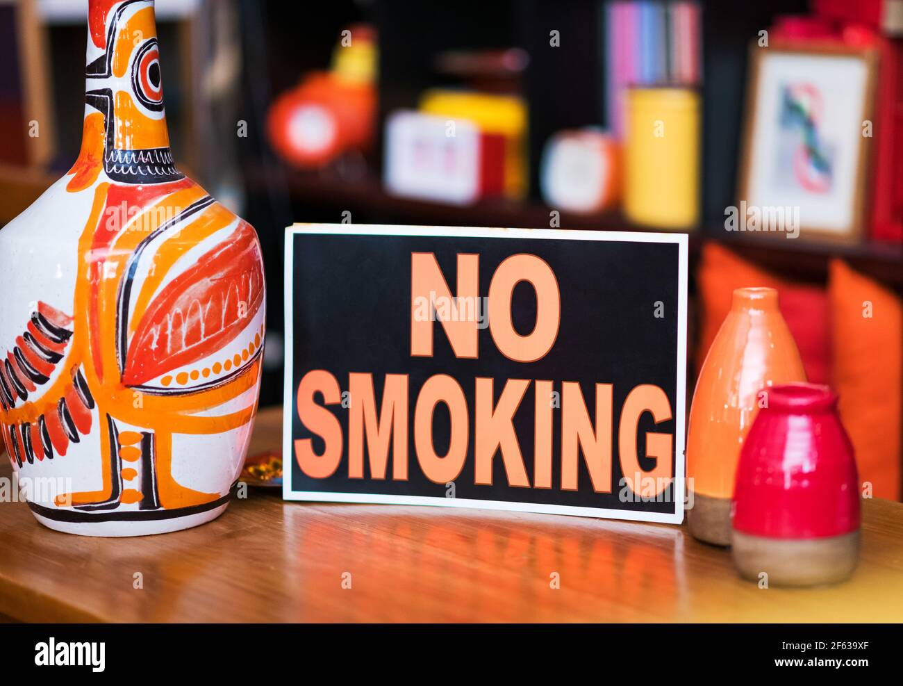 Nessun segno di fumo propped contro le ceramiche fatte a mano dai colori luminosi dentro un punto vendita avverte che si tratta di una zona non fumatori e il fumo è vietato sul pre Foto Stock