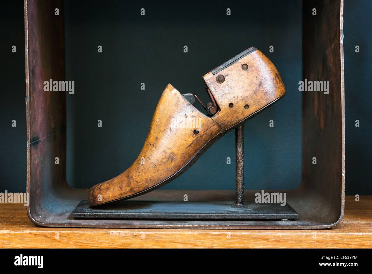 Vecchia forma di scarpe di legno d'epoca per la produzione e la riparazione di scarpe fatte a mano da un ciottolo esposto su un cavalletto un ripiano in vista laterale Foto Stock
