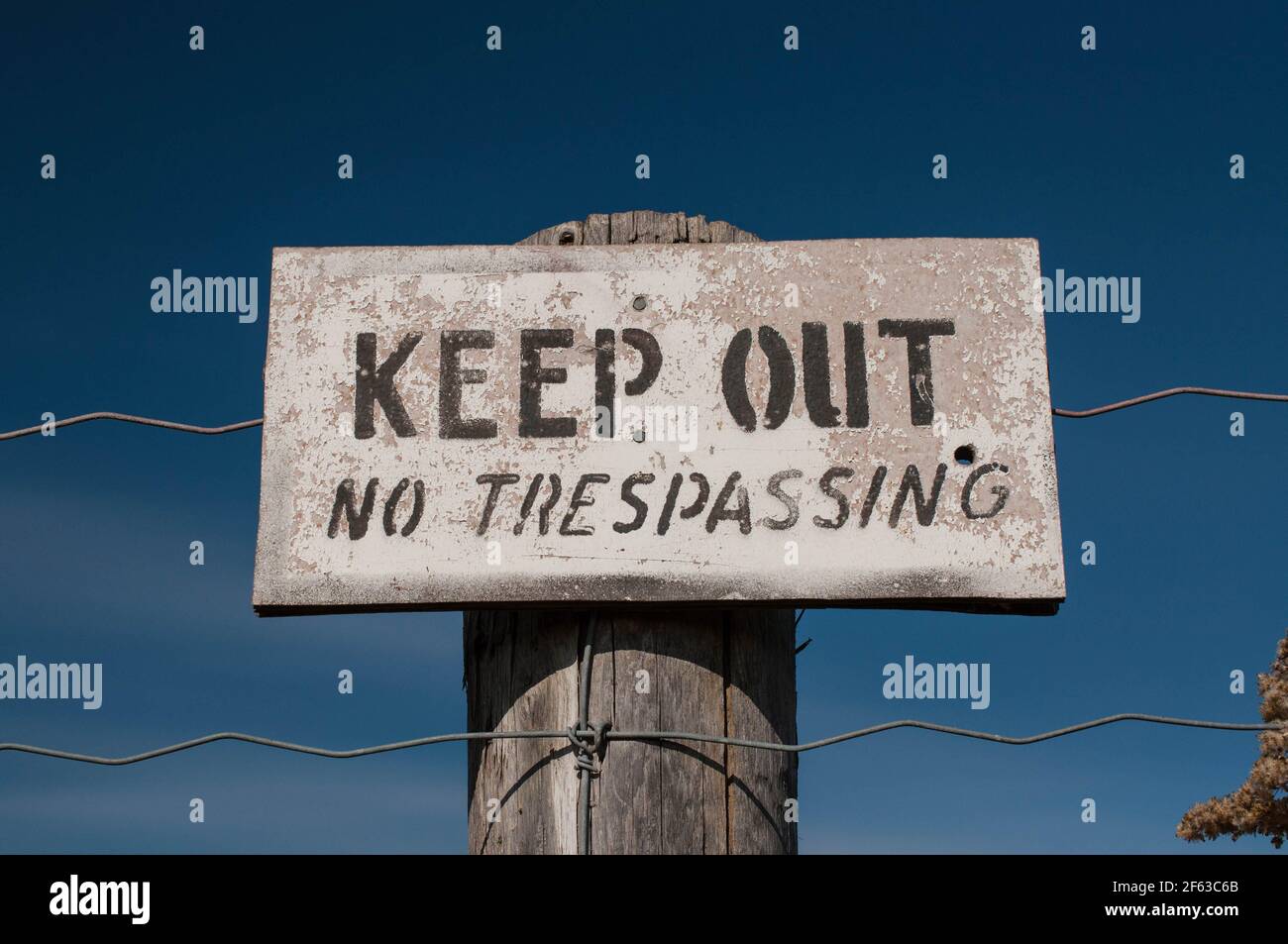 Il vecchio cartello di avvertimento su un alberino di legno legge tenersi fuori - Nessun Trespassing Foto Stock