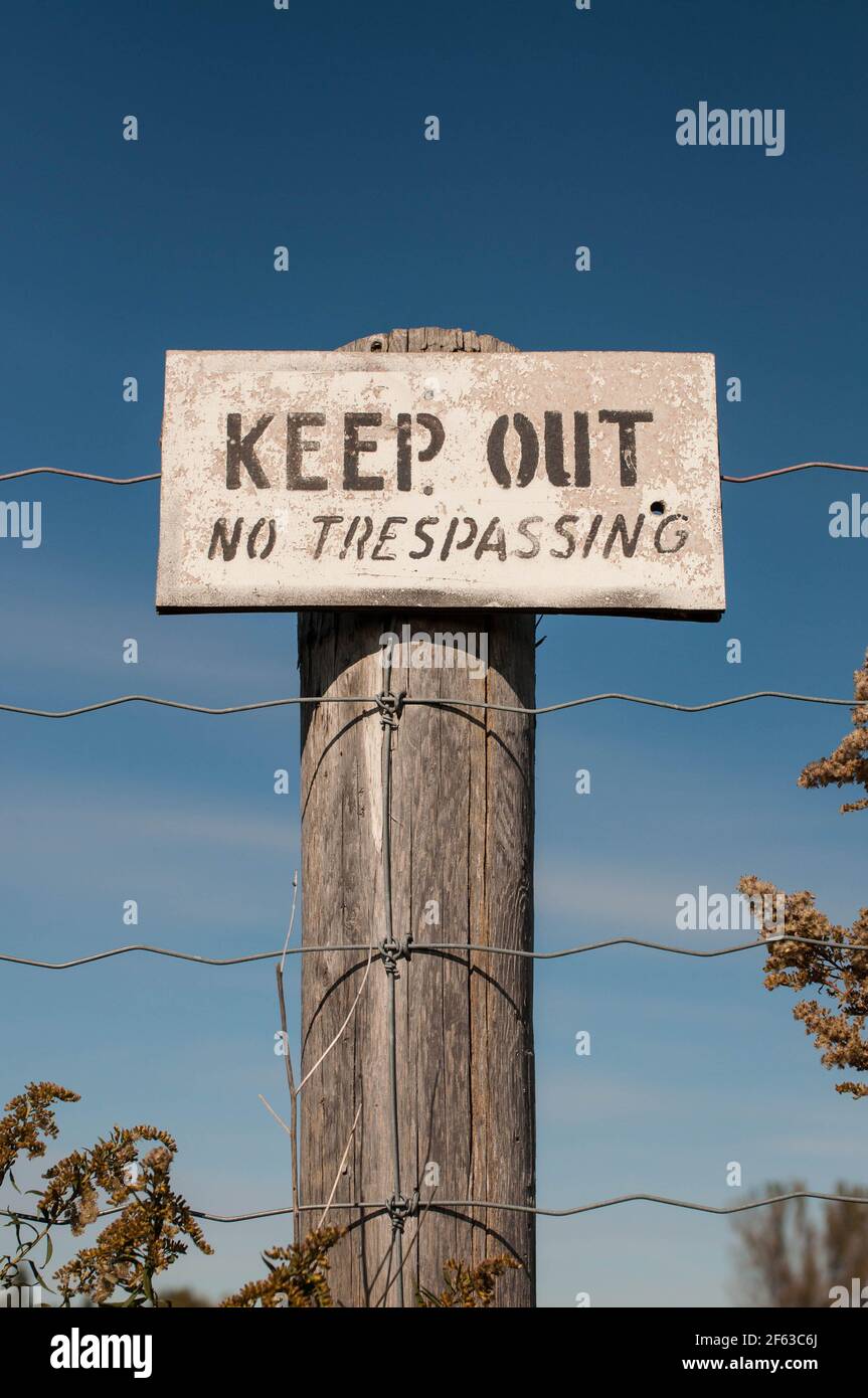 Un cartello di avvertimento su un palo di legno recita tenere fuori - Nessun Trespassing Foto Stock
