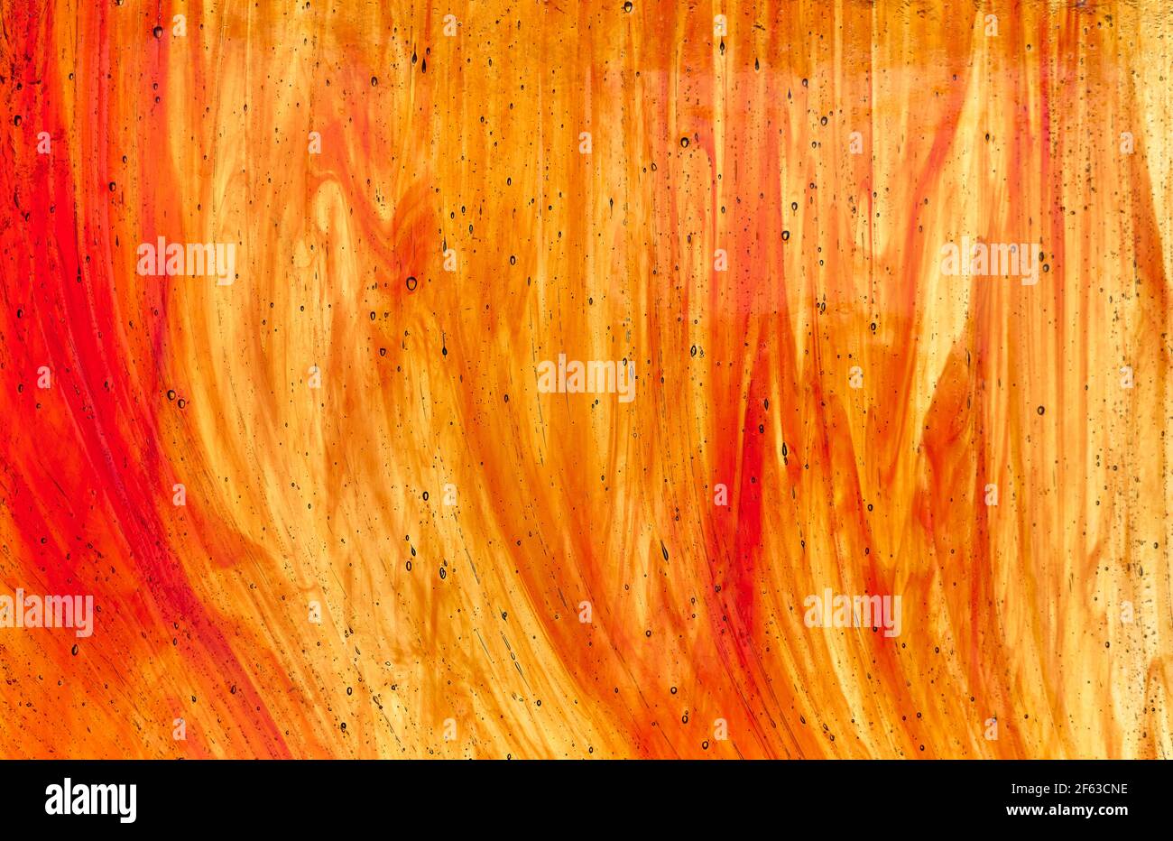 particolare di un vetro appartenente ad una vetrata con tinte arancioni scure e chiare e alcune bolle all'interno esso Foto Stock