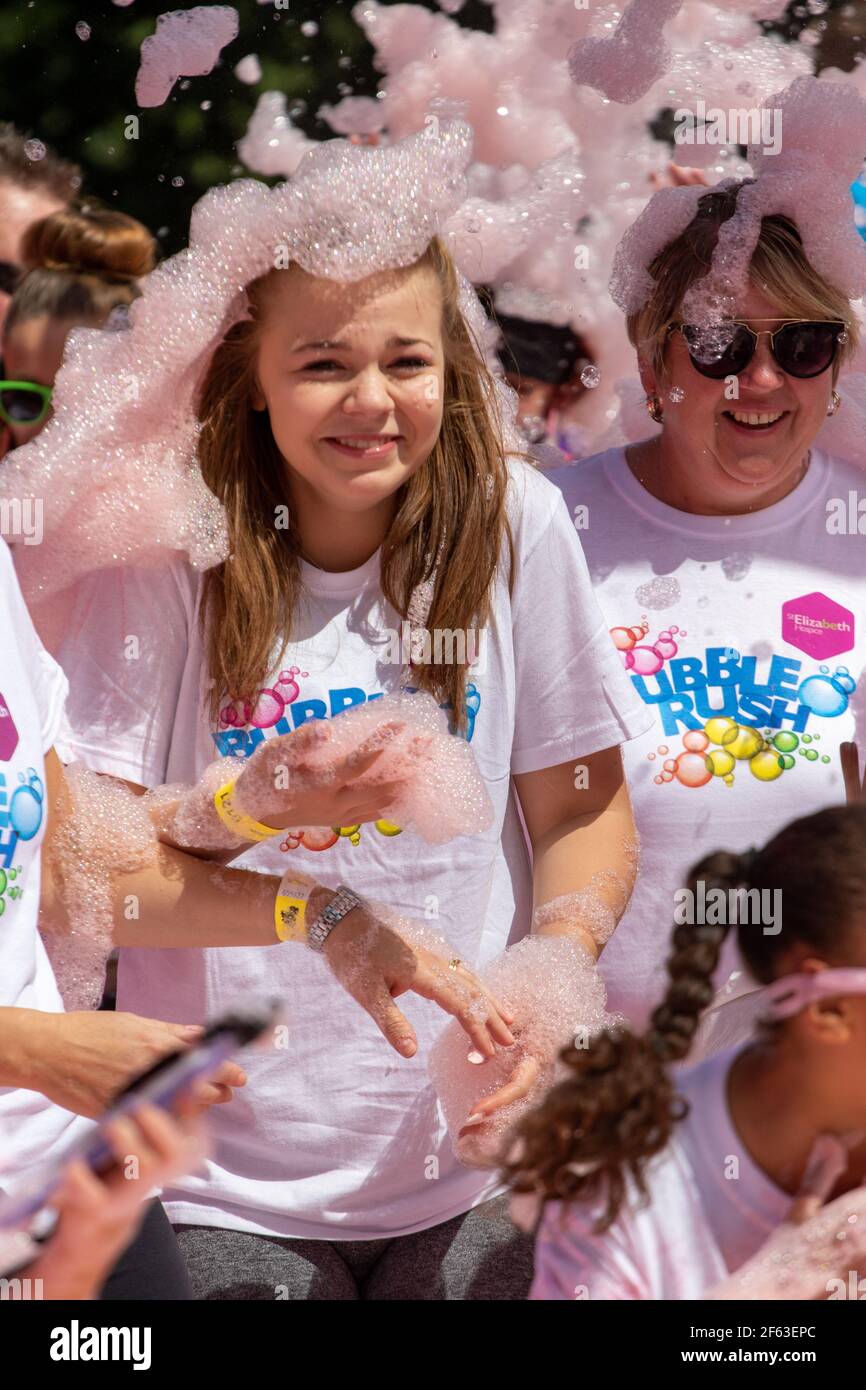 Due donne in un fondo di beneficenza che indossa schiuma rosa sulla loro testa come cappelli Foto Stock
