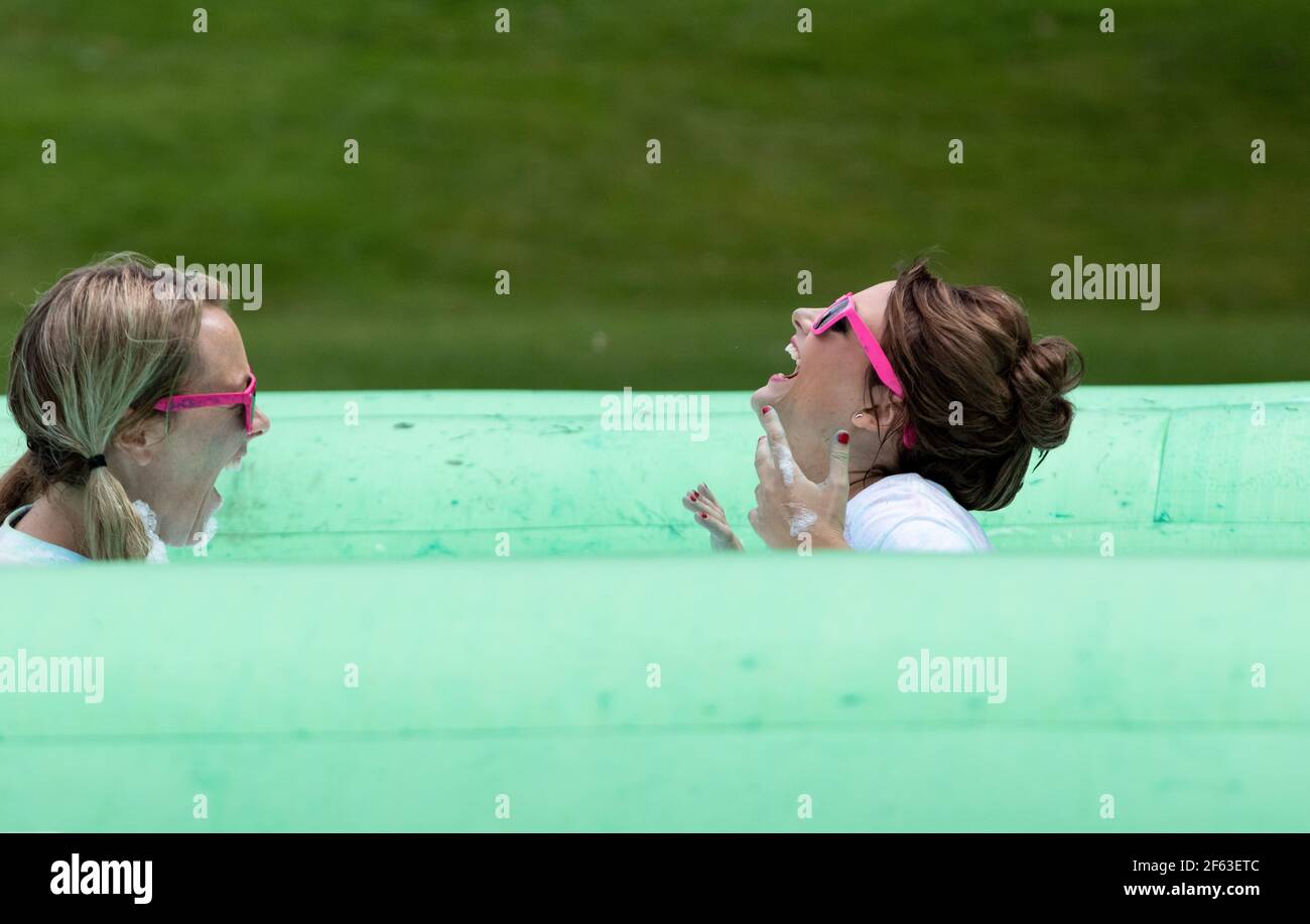 Due donne in occhiali da sole che godono di un beneficenza raccolta fondi schiuma Bubble Evento di punta Foto Stock