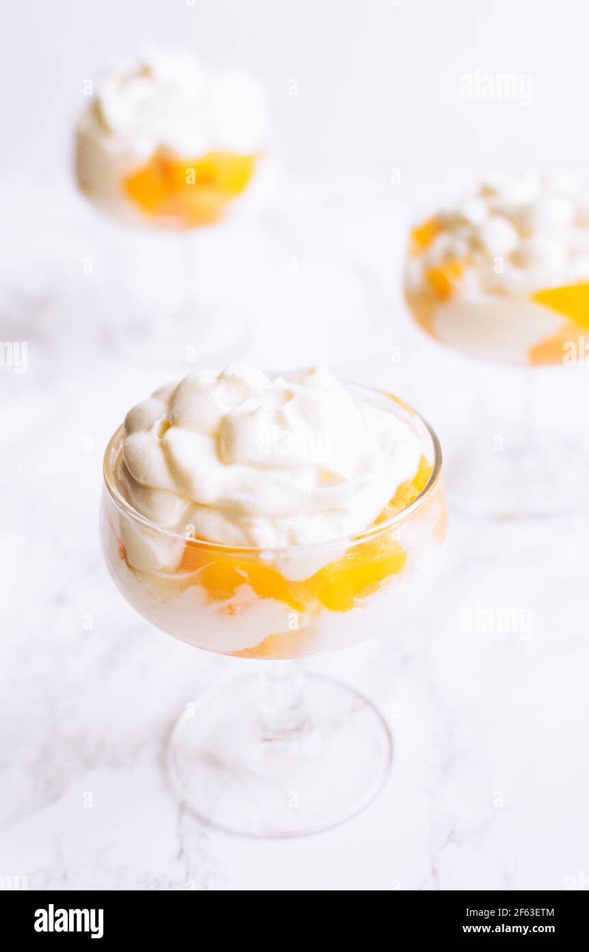 Il tiramisù, variante di tradizionali piatti Italiani creme dessert per bambini con pesche e mascarpone su sfondo bianco. Foto Stock