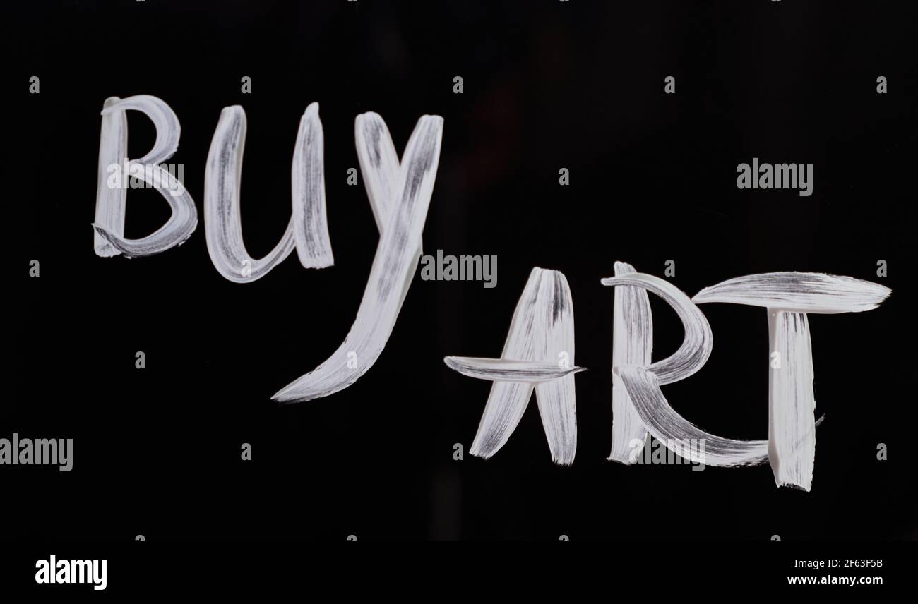 Una mano che scrive su vetro 'Buy Art'. Testo del messaggio per costringere le persone ad acquistare arte online o offline. Sfondo nero. Foto di alta qualità Foto Stock