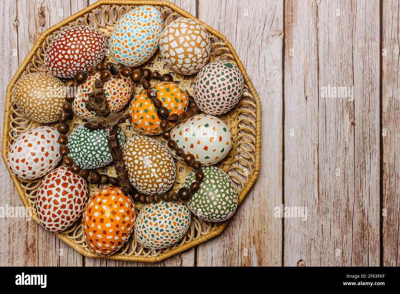 Happy Easter.colorful fatto a mano uova di Pasqua con crocifisso in legno cesto copia spazio per text.Spring decorazione sfondo. Tradizione festosa Foto Stock