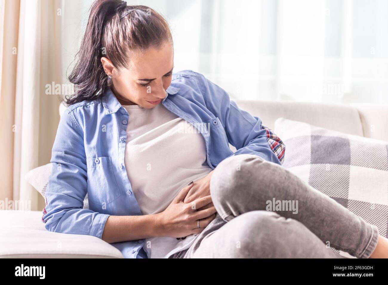 Dettaglio di una donna nel dolore di abdominals, gallbladder, ovaie, appendice, fegato o intestini che tiene il ventre con le mani. Foto Stock