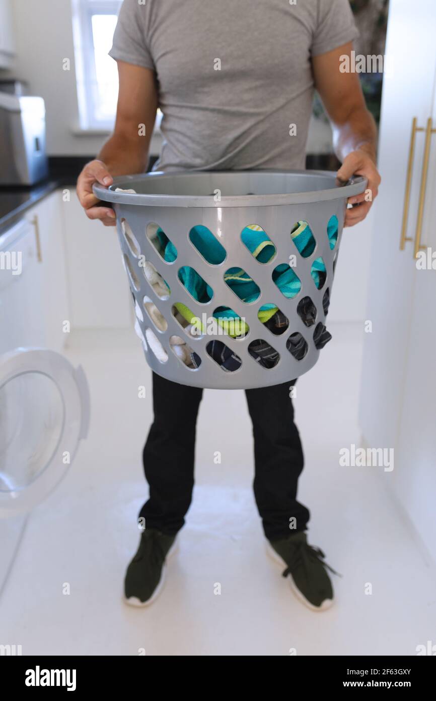 Uomo caucasico che indossa una maglietta grigia e fa lavanderia Foto Stock