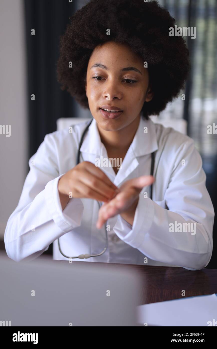 African american femmina medico seduta facendo video chiamata consultazione Foto Stock