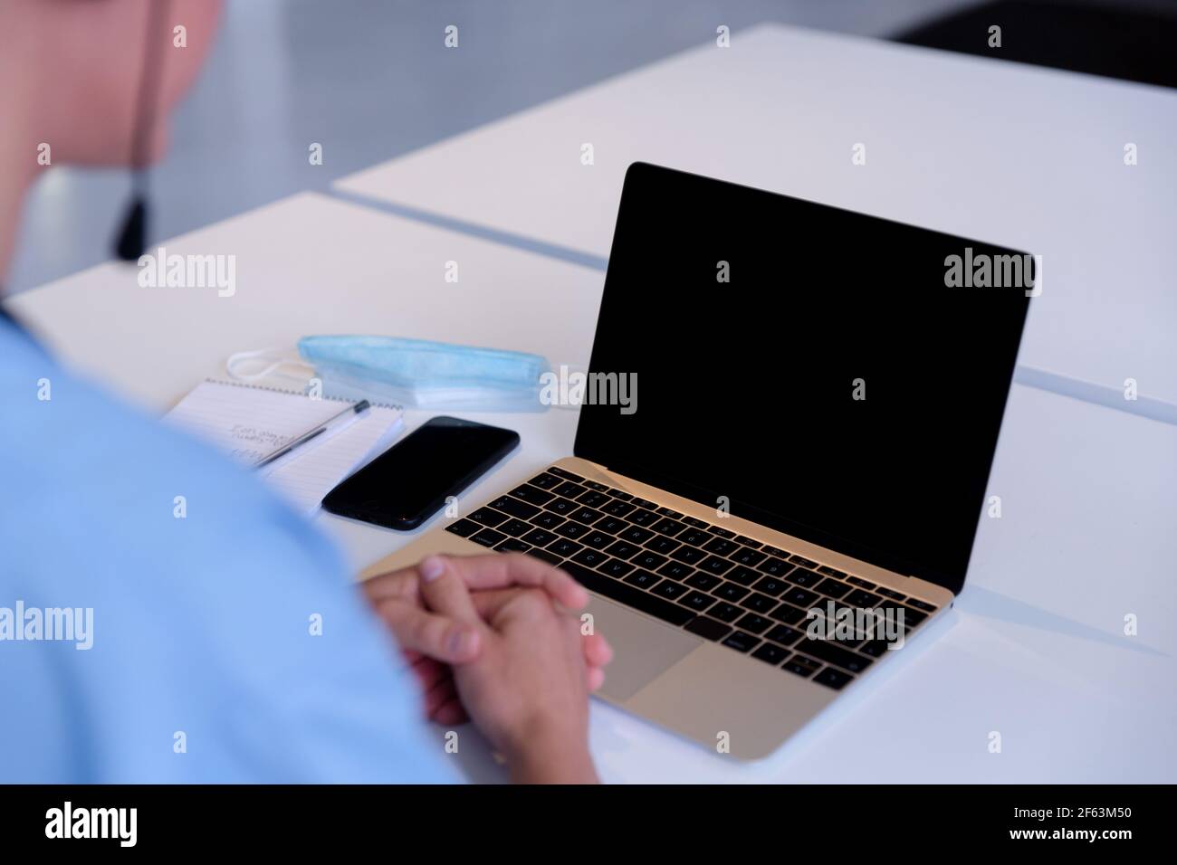 Vista sulla spalla della donna caucasica medico alla scrivania utilizzando computer portatile durante la consultazione delle videochiamate Foto Stock