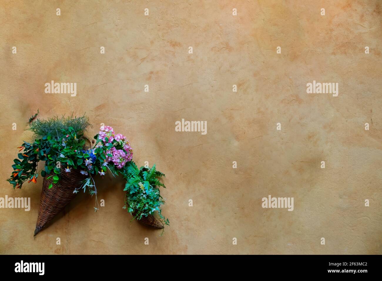 Vaso di fiori e piante fatto di Thatch appeso su un vecchio muro di argilla con uno spazio di scrittura. Foto Stock