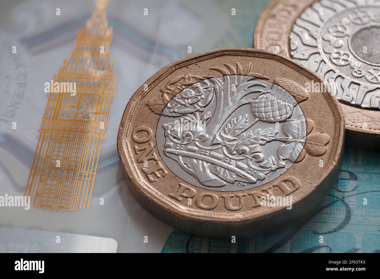 Moneta inglese da una libbra posta sulla banconota da 5 libbre di polimero con il simbolo visibile del Big ben. Concetto. Messa a fuoco selettiva. Macro. Foto Stock