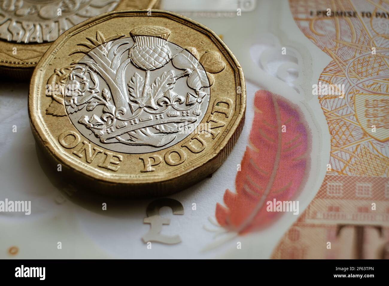 Monete inglesi da una libbra poste su una banconota da 10 libbre. Concetto. Messa a fuoco selettiva. Macro. Foto Stock