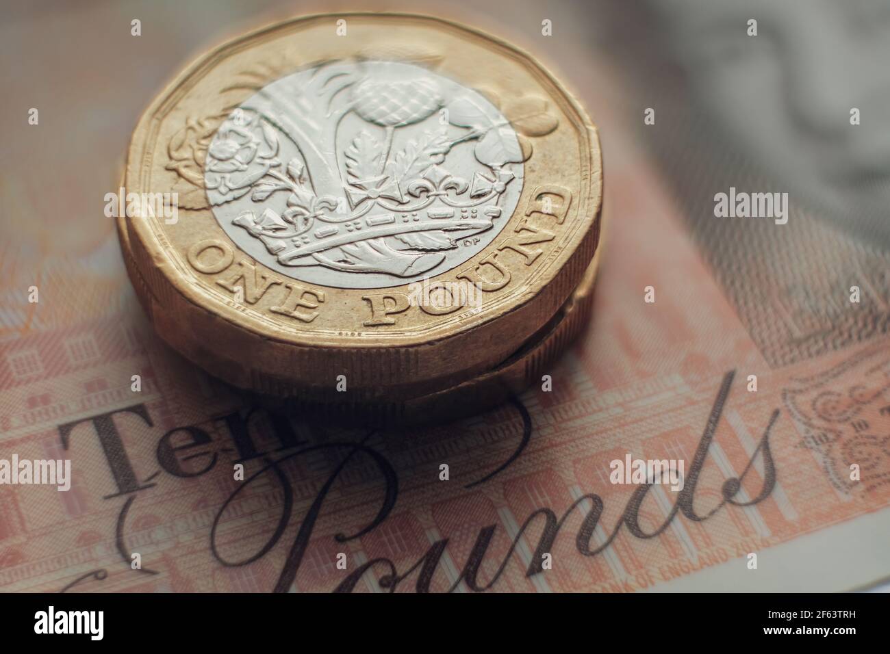 Monete inglesi da una libbra poste su una banconota da 10 libbre. Concetto. Messa a fuoco selettiva. Macro. Foto Stock