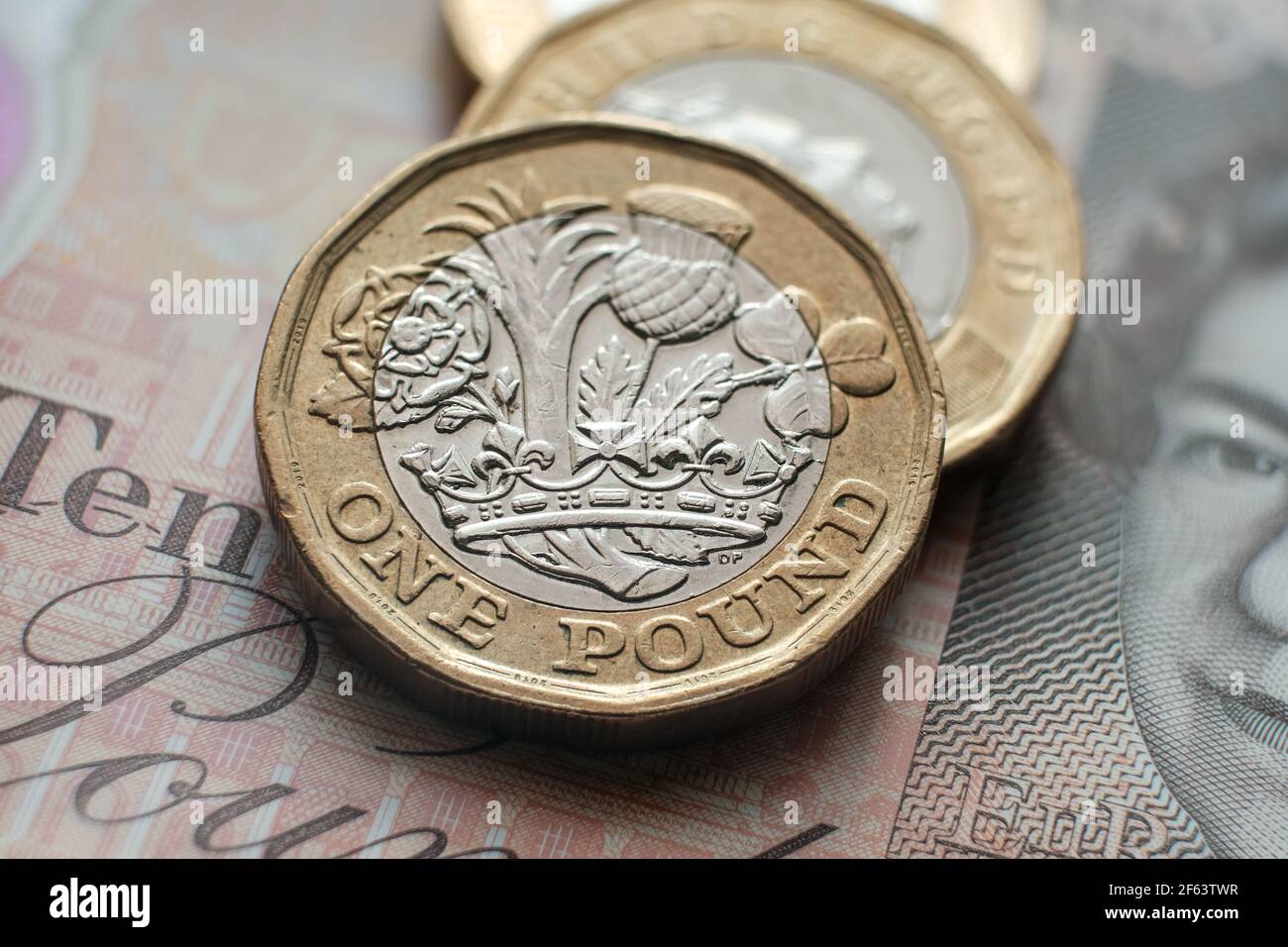 Monete inglesi da una libbra poste su una banconota da 10 libbre. Concetto. Messa a fuoco selettiva. Macro. Foto Stock